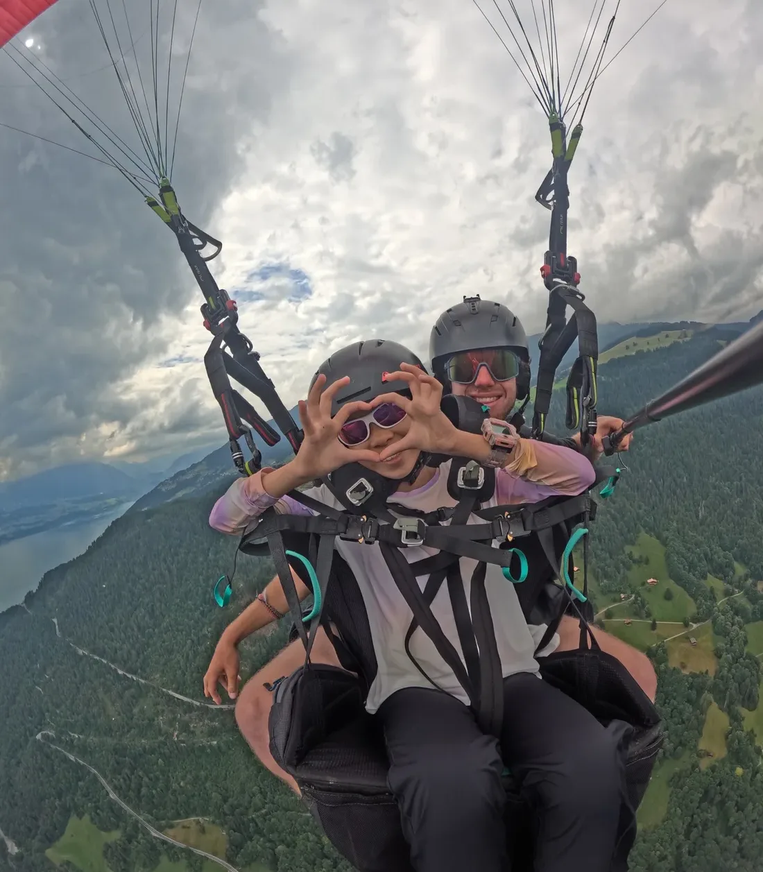 Deux personnes souriantes pendant un vol en parapente biplace en Valais.